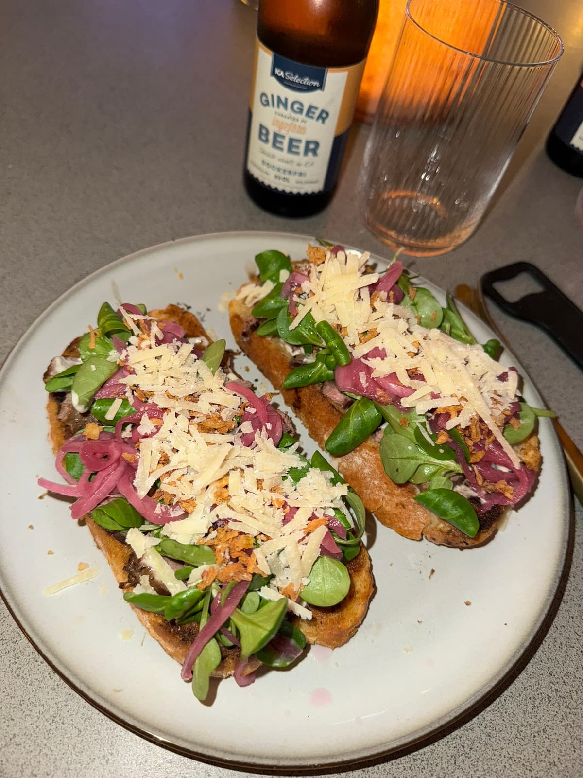 Två öppna smörgåsar med sallad, rödlök och riven ost